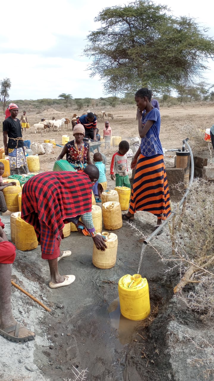 Multi-generational community gathered around the reliable water point with livestock